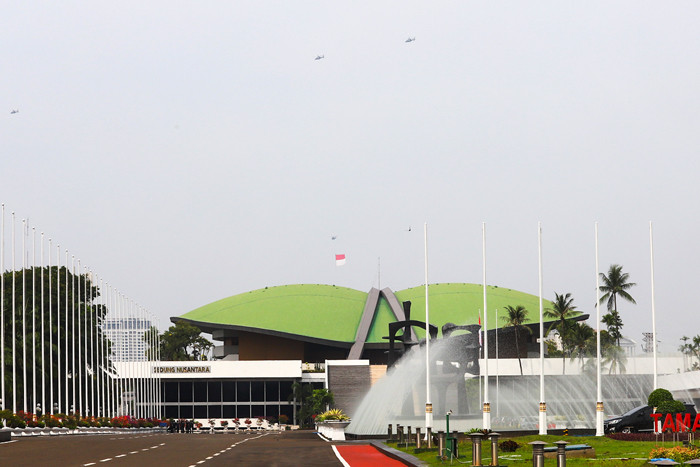 Helikopter TNI terbang dengan mengibarkan bendera Merah Putih dan Lambang TNI melintas di atas gedung nusantara, Jakarta, Selasa (5/10/2021).