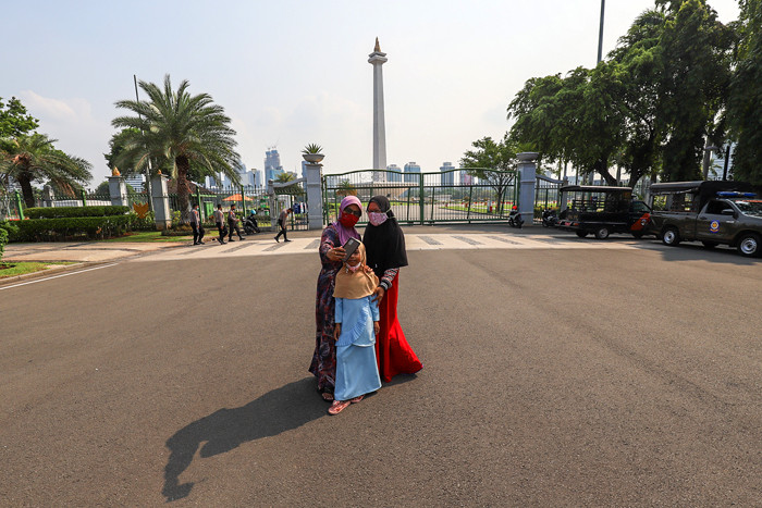 Pengunjung dan sejumlah petugas pengamanan saat berada di kawasan Monas, Jakarta Pusat, Kamis (7/10/2021).