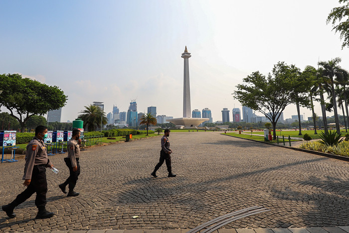 Pengunjung dan sejumlah petugas pengamanan saat berada di kawasan Monas, Jakarta Pusat, Kamis (7/10/2021).