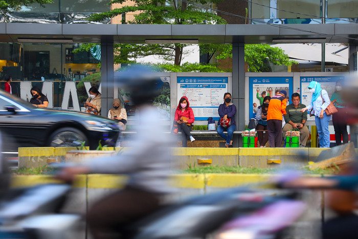 Para pekerja milenial saat menunggu transportasi umum di halte kawasan Sudirman, Jakarta, Jumat (8/10/2021).