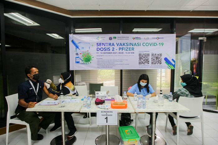 Petugas vaksinator memberikan suntikan vaksin Covid-19 jenis Pfizer untuk warga di Sentra Vaksinasi Gedung HighEnd MNC Center, Jakarta, Selasa (12/10/2021).