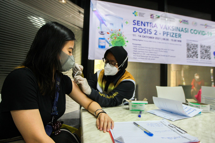 Petugas vaksinator memberikan suntikan vaksin Covid-19 jenis Pfizer untuk warga di Sentra Vaksinasi Gedung HighEnd MNC Center, Jakarta, Selasa (12/10/2021).