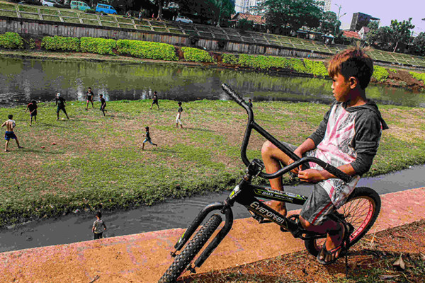 Sejumlah remaja memanfaatkan dataran sedimentasi lumpur kering untuk bermain sepak bola di kawasan Banjir Kanal Timur, Jakarta Timur, Rabu (13/10/2021).