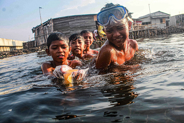 Sejumlah anak-anak sedang berenang di dermaga kapal nelayan, Cilincing, Jakarta Utara, Jumat (15/10/2021).