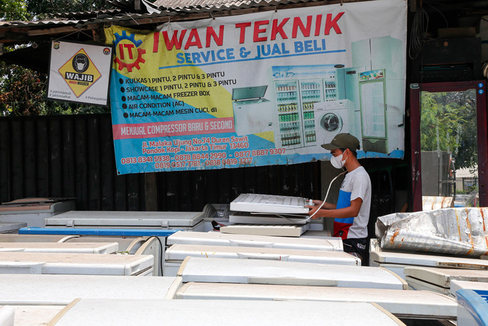 Iwan (26) memeriksa kulkas bekas di bengkel reparasi 'Iwan Teknik' di Jalan I Gusti Ngurah Rai, Cakung, Jakarta Timur, Sabtu (16/10/2021).