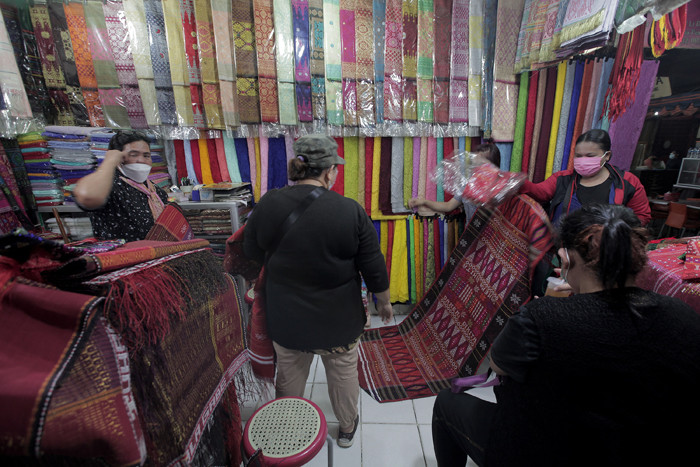 Calon pembeli memilih kain ulos yang dijual di Pasar Senen, Jakarta Pusat, Jumat (15/10/2021).