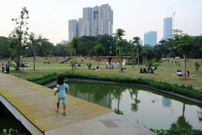 Warga menikmati suasana menjelang sore di Hutan Kota GBK Jakarta, Minggu (17/10/2021).