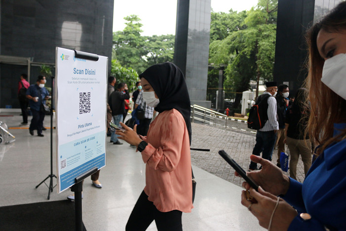 Para pengunjung dan pegawai melakukan scan identitas melalui aplikasi PeduliLindungi saat akan memasuki gedung PN Jakarta Pusat, Selasa (19/10/2021).