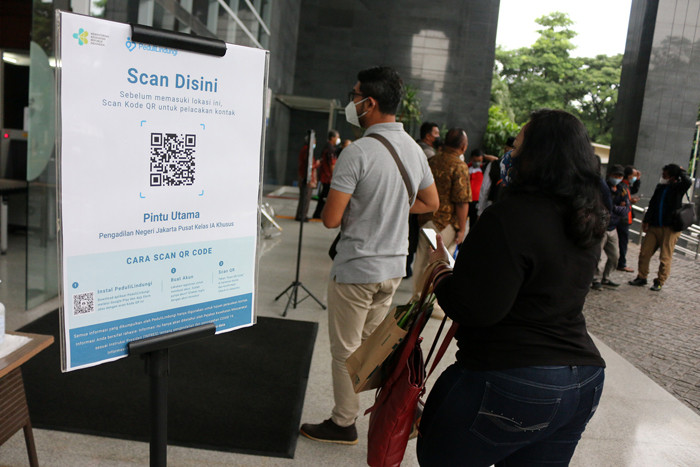 Para pengunjung dan pegawai melakukan scan identitas melalui aplikasi PeduliLindungi saat akan memasuki gedung PN Jakarta Pusat, Selasa (19/10/2021).