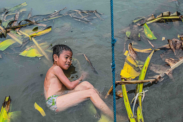 Anak-anak sedang bermain tanpa menggunakan masker di tepi sungai, Jakarta, Selasa (19/10/2021).