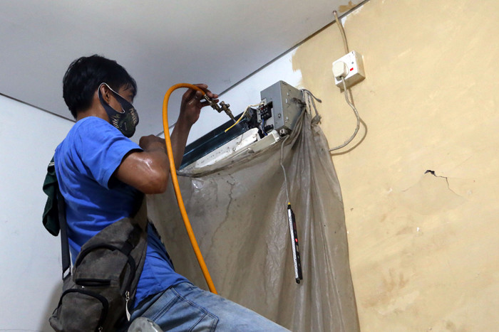 Teknisi membersihkan Air conditioner (AC) disalah satu rumah pelanggan di Surabaya, Jawa Timur, Senin (25/10/2021).