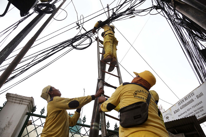Petugas Dinas Bina Marga DKI Jakarta menata instalasi kabel yang semrawut di kawasan Wolter Monginsidi, Jakarta Selatan, Rabu, (27/10/2021).