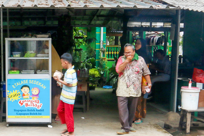 Relawan Yayasan Nasi Jumat (SiJum) Indonesia mengajak warga untuk menikmati makan siang di Warung Makan Gratis, Depok, Jawa Barat, Jumat (29/10/2021).