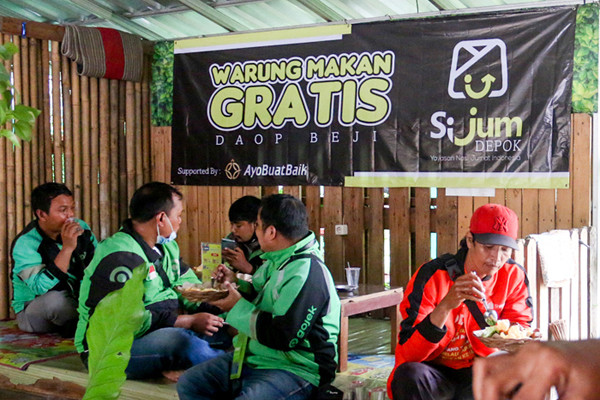 Relawan Yayasan Nasi Jumat (SiJum) Indonesia mengajak warga untuk menikmati makan siang di Warung Makan Gratis, Depok, Jawa Barat, Jumat (29/10/2021).