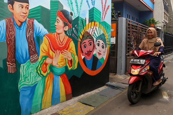 Warga melintas di gang bergambar mural dengan tema budaya Betawi di kawasan Kampung Sentra Kreatif di Kota Bambu Selatan, Jakarta Barat, Selasa (2/11/2021).
