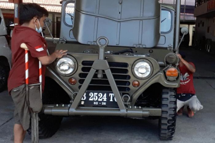 Pitono tengah memperbaiki mobil Jeep.