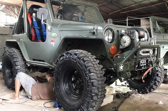 Pitono tengah memperbaiki mobil Jeep.