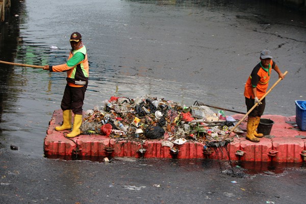 Pekerja membersihkan sampah plastik dan ranting pohon dialiran kali Item, Jakarta, Sabtu (13/11/2021).