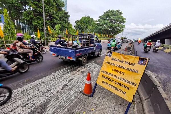 Kendaraan saat melintasi jalan yang sedang dalam proses perbaikan di Jalan Gatot Subroto, Jakarta, Rabu (17/11/2021).