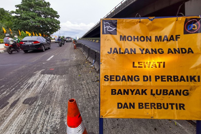 Kendaraan saat melintasi jalan yang sedang dalam proses perbaikan di Jalan Gatot Subroto, Jakarta, Rabu (17/11/2021).