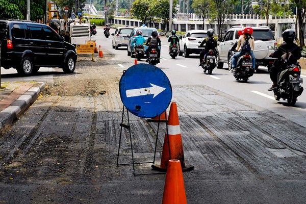 Kendaraan saat melintasi jalan yang sedang dalam proses perbaikan di Jalan Gatot Subroto, Jakarta, Rabu (17/11/2021).