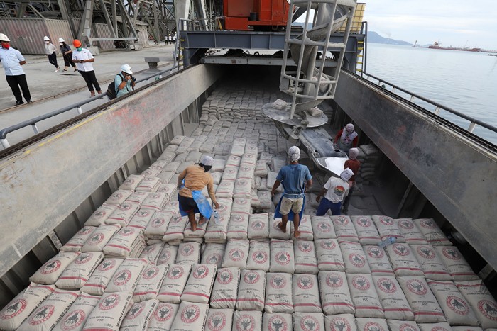 Pekerja memindahkan karung semen ke atas kapal di dermaga Semen Padang, Teluk Bayur, Padang, Sumatera Barat, Rabu (24/11/2021).