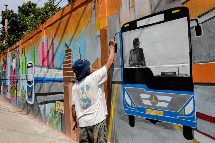 Petugas PPSU menyelesaikan pembuatan mural bertema 'Kota Jakarta' di kawasan Tanah Kusir, Kebaroyan Lama, Jakarta Selatan, Jumat (26/11/2021).