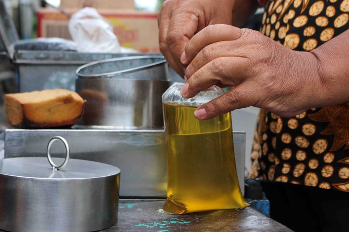 Pedagang minyak goreng curah menuangkan minyak di kawasan jalan serdang Kemayoran Jakarta, Sabtu (27/11/2021).