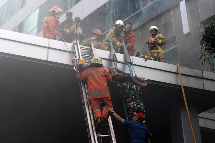 Petugas mengevakuasi korban kebakaran yang terjadi di Gedung Cyber 1, Jakarta, Kamis (2/12/2021).