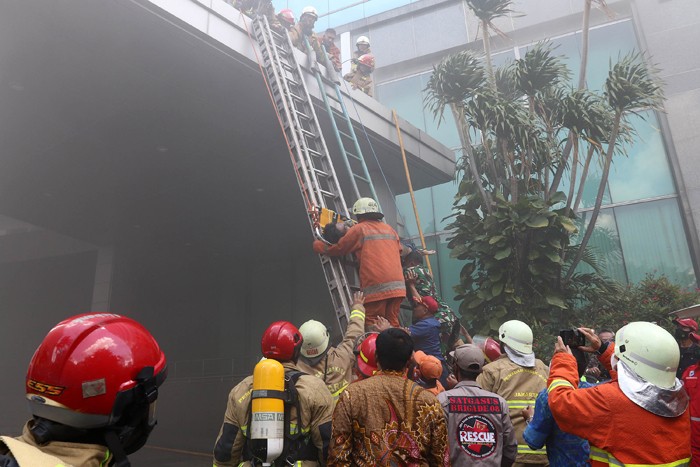 Petugas mengevakuasi korban kebakaran yang terjadi di Gedung Cyber 1, Jakarta, Kamis (2/12/2021).