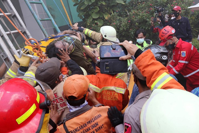 Petugas mengevakuasi korban kebakaran yang terjadi di Gedung Cyber 1, Jakarta, Kamis (2/12/2021).