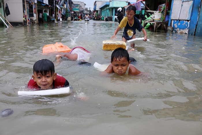 Warga bermain air luapan pasang air laut yang mengenangi pemukiman warga di kawasan Muara Angke, Jakarta Utara, Sabtu (4/12/2021).