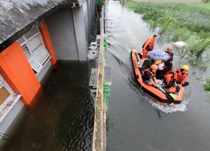 Sejumlah warga melewati banjir untuk mengungsi ketempat yang lebih aman di Makassar, Selasa (7/12/2021).