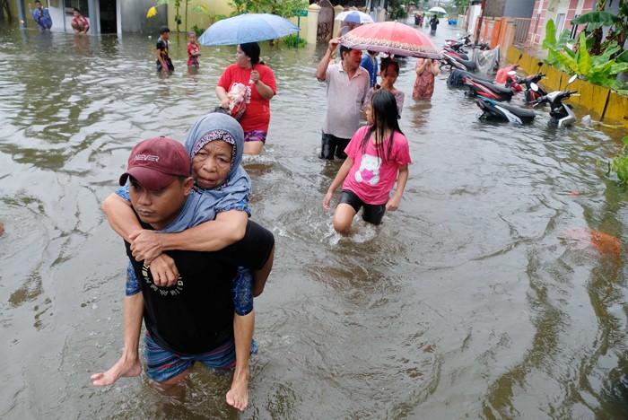 Sejumlah warga melewati banjir untuk mengungsi ketempat yang lebih aman di Makassar, Selasa (7/12/2021).