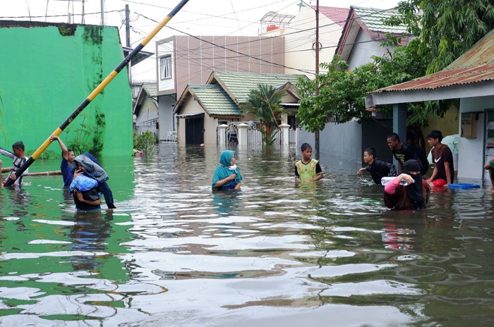 Warga menerobos banjir di Kompleks Perumahan Swadaya Mas, Keluarahan Batua, Kecamatan Manggala, Makassar, Sulawesi Selatan, Selasa (7/12/2021).