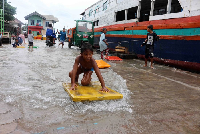 Anak-anak bermain luapan air laut yang menggenangi dermaga di pulau Panggang Kepulauan Seribu Utara, Provinsi DKI Jakarta, Selasa (7/12/2021).