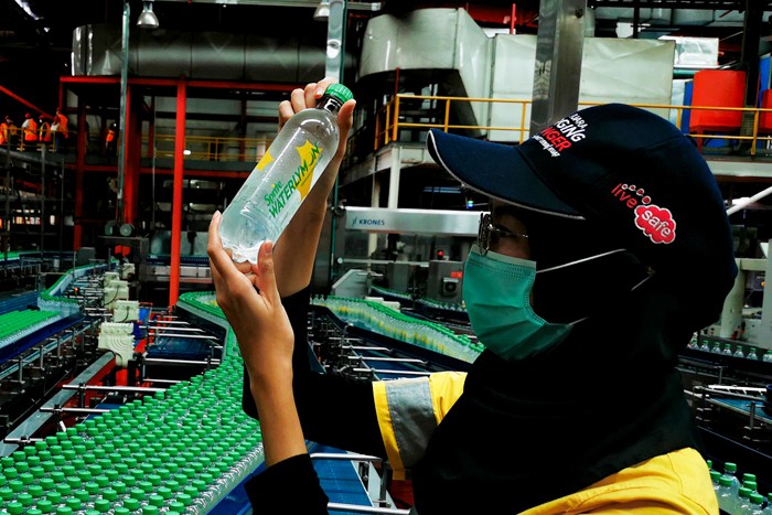 Pekerja saat mengecek produk pada proses pembuatan minuman menyegarkan, berkualitas tinggi dan aman di Pabrik Coca-Cola.