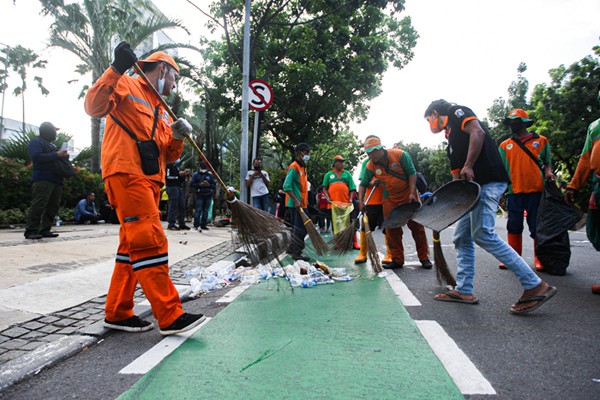 Sejumlah petugas gabungan PPSU dan Dinas Lingkungan Hidup gerak cepat membersihkan sampah sisa unjuk rasa buruh di Jalan Merdeka Selatan.