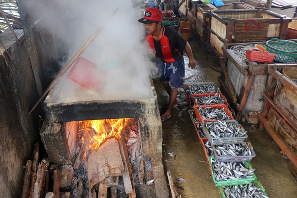 Pekerja merebus ikan yang sudah direndam garam untuk dijadikan ikan asin di pemukiman Nelayan, Muara Angke, Jakarta, Sabtu (11/12/2021).