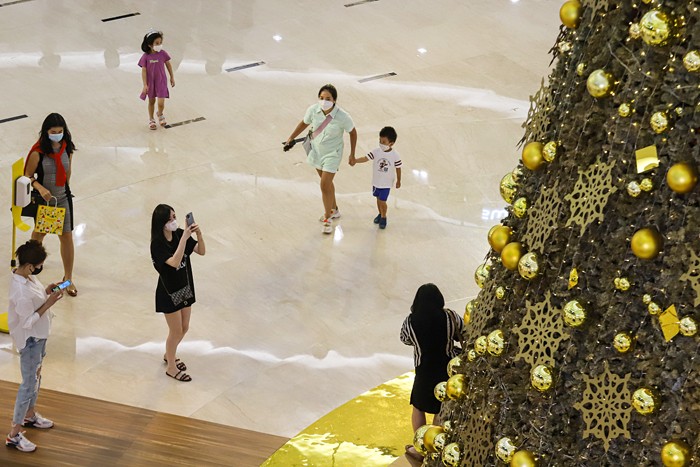Pengunjung berfoto dengan latar belakang instalasi Golden Giant Christmas Tree di Atrium Pusat Perbelanjaan Senayan City, Jakarta Pusat, Selasa (14/12/2021).