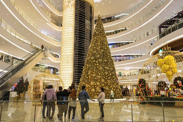 Pengunjung berfoto dengan latar belakang instalasi Golden Giant Christmas Tree di Atrium Pusat Perbelanjaan Senayan City, Jakarta Pusat, Selasa (14/12/2021).