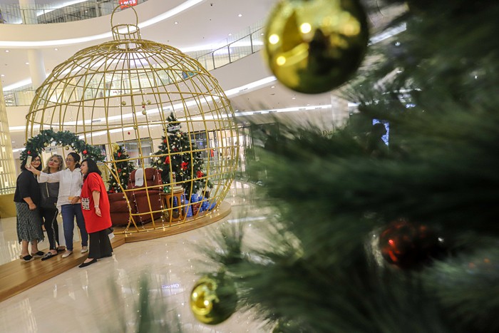 Pengunjung berfoto dengan latar belakang instalasi Golden Giant Christmas Tree di Atrium Pusat Perbelanjaan Senayan City, Jakarta Pusat, Selasa (14/12/2021).