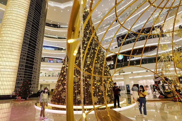 Pengunjung berfoto dengan latar belakang instalasi Golden Giant Christmas Tree di Atrium Pusat Perbelanjaan Senayan City, Jakarta Pusat, Selasa (14/12/2021).