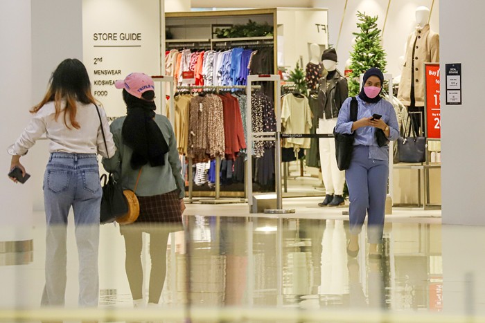 Pengunjung berjalan di depan toko di Pusat Perbelanjaan Senayan City, Jakarta Pusat, Selasa (14/12/2021).