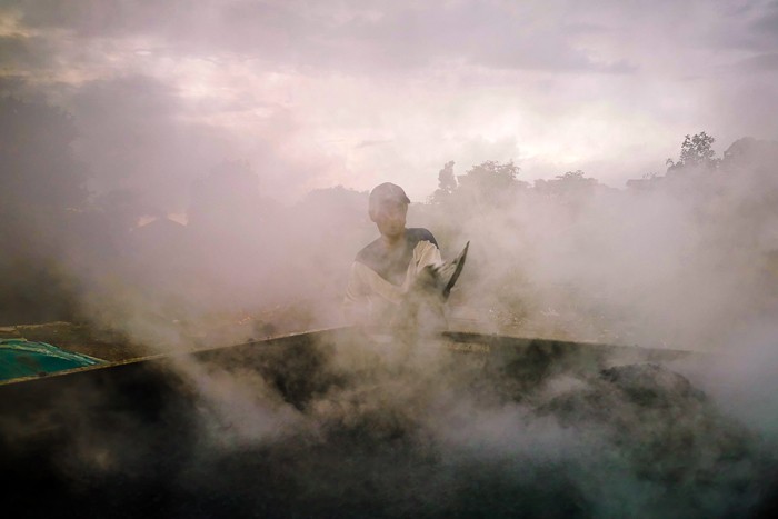 Potret Para pekerja sedang menggoreng campuran pasir dan campuran aspal secara manual di lahan kosong, Bandung, Jawa Barat, Minggu (19/12/2021).