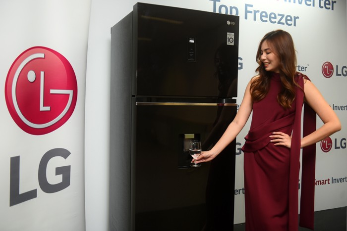 Model berpose disamping kulkas dua pintu yang tampil unik dengan keberadaan dispenser air melekat pada bilah pintunya di Jakarta, Selasa (21/12/2021).