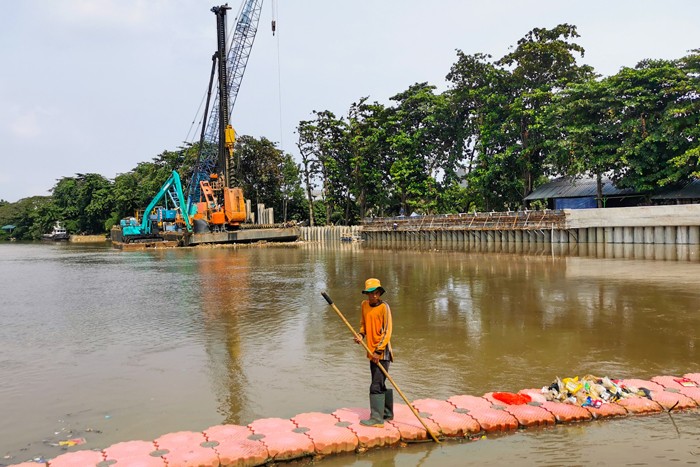 Pekerja dengan alat berat saat menyelesaikan pemasangan dinding turap atau sheetpile di aliran kali PIK, Jakarta Utara, Selasa (21/12/2021).