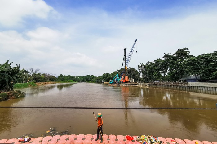 Pekerja dengan alat berat saat menyelesaikan pemasangan dinding turap atau sheetpile di aliran kali PIK, Jakarta Utara, Selasa (21/12/2021).