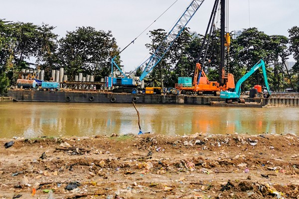 Pekerja dengan alat berat saat menyelesaikan pemasangan dinding turap atau sheetpile di aliran kali PIK, Jakarta Utara, Selasa (21/12/2021).