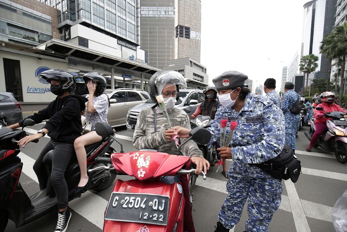 Sejumlah perserta aksi yang tergabung dalam Forum Kader Bela Negara DKI Jakarta menggelar aksi membagikan bunga dan masker kepada pengguna jalan.